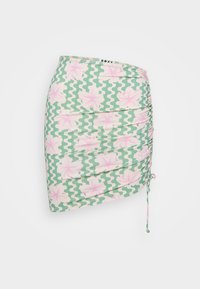 Grønn mini skjørt med rosa blomster mønster og hvite sikk-sakk detaljer. Har rynking på siden og en knytedetalj for justering.