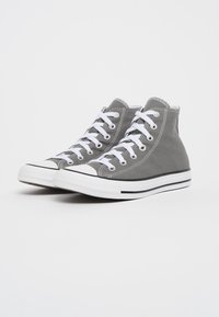 Grijze hoge sneakers van canvas met witte veters, rubberen neusbeschermers en twee zwarte strepen langs de witte tussenzool.
