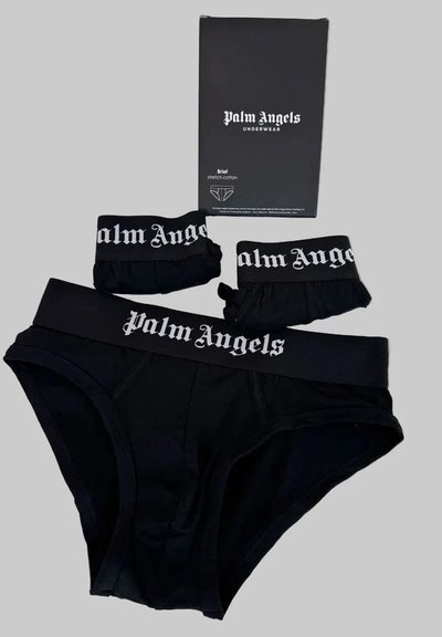 Μαύρα βαμβακερά εσώρουχα Palm Angels με άσπρη λωρίδα μέσης με λογότυπο, εμφανίζονται με δύο διπλωμένα ζευγάρια και μία μαύρη κουτί με μπραντζάρισμα σε γκρι φόντο.