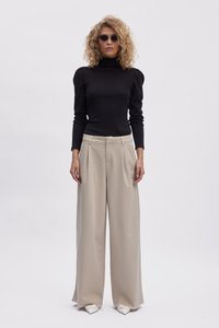Musthave musta turtleneck, mis on kokku pandud kõrge vöökohtadega laiadest beežidest pükstest. Aksessuaarid, sealhulgas nurksed prillid ja terava ninaga valged kingad.