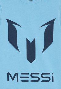 T-shirt bleu clair avec un logo bleu foncé comportant des formes aigües et le texte "MESSI" dans une police moderne et en gras.