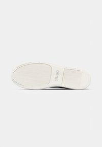 Semelle de chaussure décontractée blanche avec motif de grip texturé, sections de bande de roulement rectangulaires et ovales, et logo "HUGO" embossé au centre.