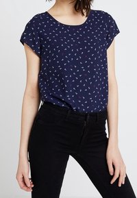 Mörkblå kortärmad topp med rundad halsringning, prydd med ett litet anktryck i vitt och rosa. Mjukt, lätt material.