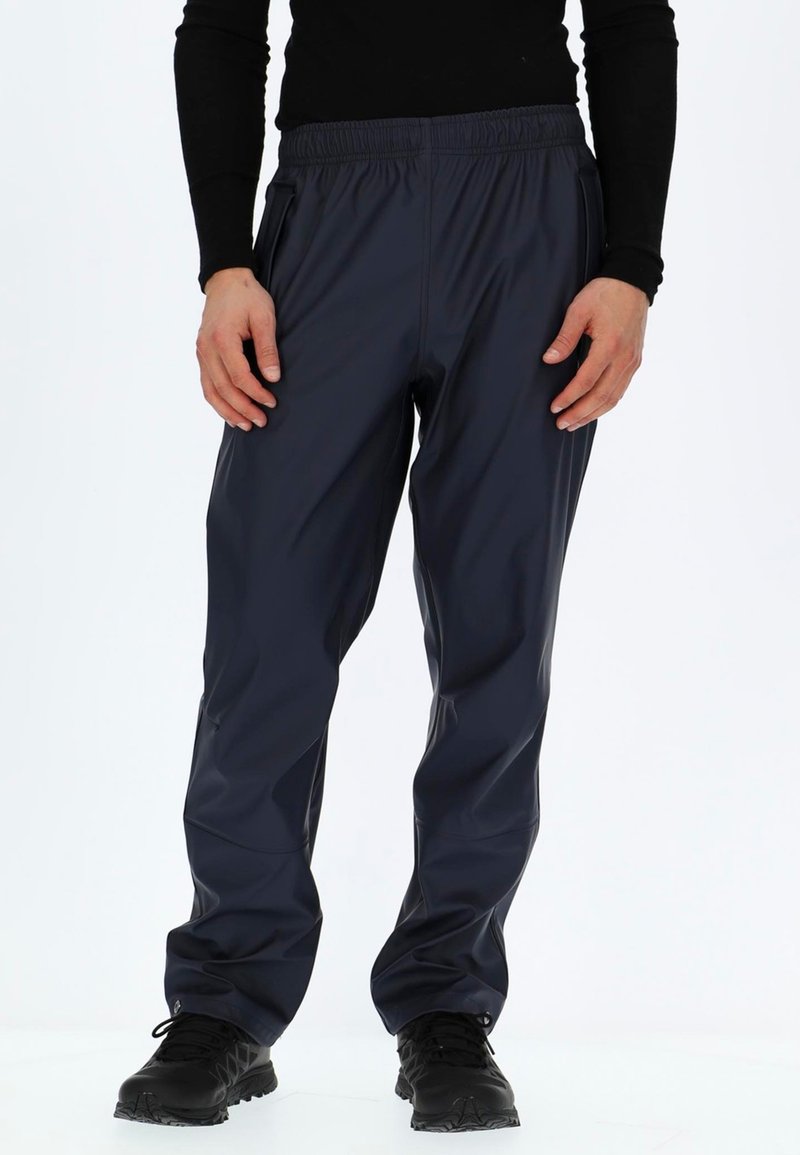 Navy wasserdichte Hosen mit elastischem Bund, seitlichen Taschen, tailliertem Design und glatter Textur, kombiniert mit schwarzen Sportschuhen.