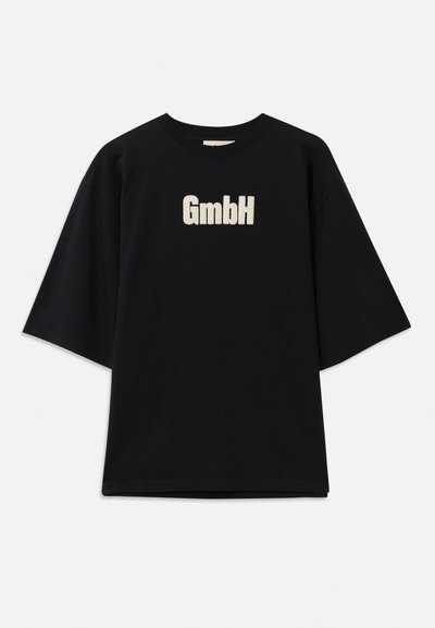 Juoda per didelė trumpomis rankovėmis marškinėliai su baltu „GmbH“ tekstu, centruotu priekyje.