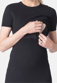 Musta ribbed-mekko lyhyillä hihoilla, istuva malli, jossa on huomaamaton aukko helppoa pääsyä varten. Pehmeä kangas, vartalonmyötäinen siluetti.