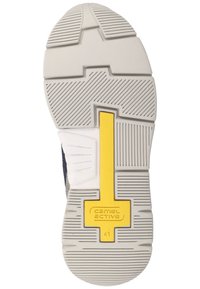 Sohle eines Sneakers mit einer weißen Gummibasis, die über strukturierte Grip-Muster verfügt, einem grauen Mittelteil und einem gelben Akzent in der Mitte.