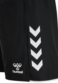 Schwarze Sportsshorts mit weißem Hummel-Bienenlogo nahe dem Saum und vier weißen nach unten gerichteten Chevrons entlang der Seitennaht.