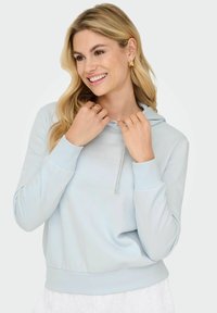 Jasnoniebieska bluza z kapturem, z sznurkiem, mankietami i pasem o prążkowanej fakturze. Gładka powierzchnia i luźny krój, z delikatnym blaskiem.