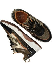 Sportieve sneakers met een mix van zwarte, gouden en bruine materialen, met een gestructureerde afwerking, ademend mesh en contrasterende accenten.