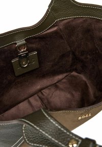 Vista interna di una borsa in pelle e camoscio verde oliva, con rivestimento morbido marrone e chiusura a gancio metallico.