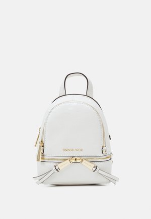 White pebbled leather backpack with rounded shape, gold hardware, dual zip closures, and adjustable straps. Michael Kors branding featured.