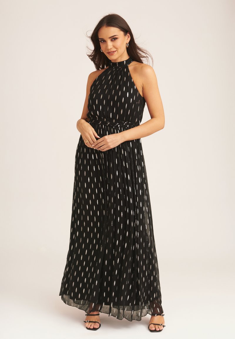 Black, halter-neck maxi dress with a pleated design, featuring a silver pattern resembling teardrops, and a thin belt at the waist.