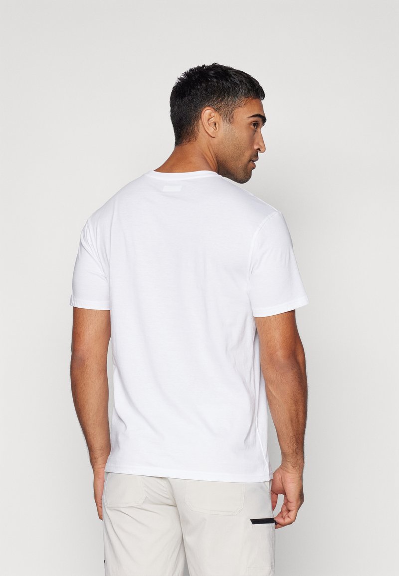 Camiseta blanca de algodón con mangas cortas, escote redondo y una textura suave. La vista trasera muestra un diseño liso con un pequeño detalle en el cuello.