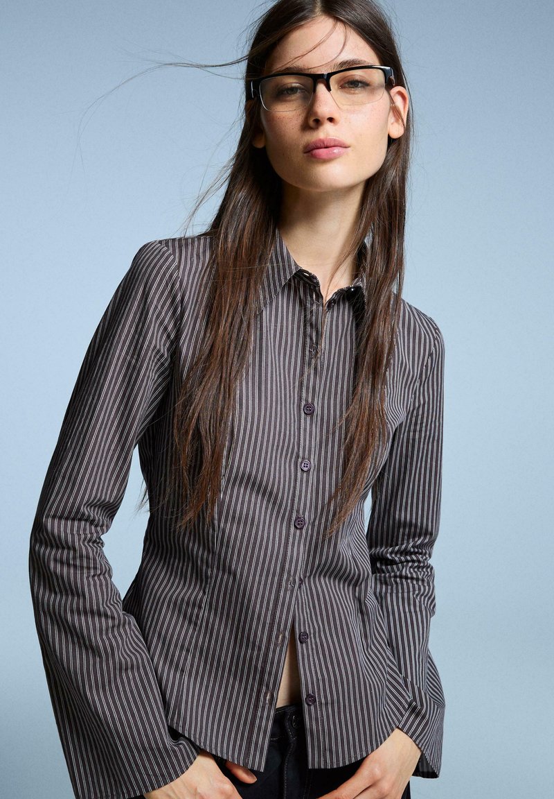 Striped button-up shirt in dark gray with light gray vertical stripes, featuring a classic collar, long flared sleeves, and button details.