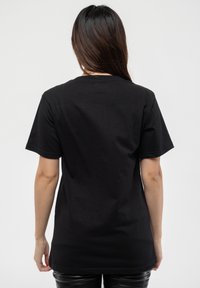 Black cotton t-shirt with short sleeves and a crew neckline. Smooth texture and straight-cut design, showcasing a plain back without graphics.