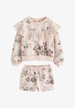 Roze gebloemd langarmshirt met oogjeskant volant en bijpassende elastische taille short, beide met paars- en groene bloemenpatronen.