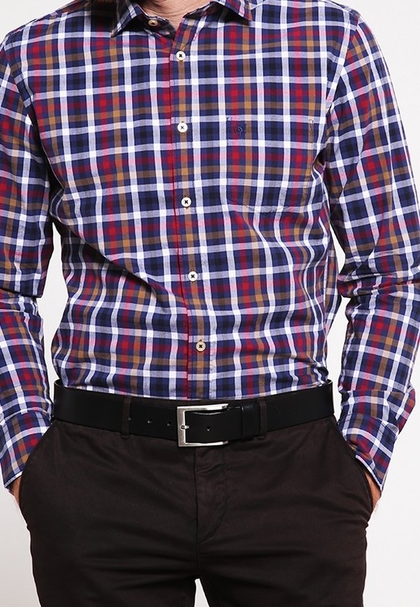 Homme portant une chemise à carreaux boutonnée à manches longues en bleu, blanc, rouge et marron avec un pantalon noir et une ceinture noire avec une boucle argentée.