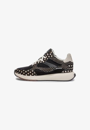 Baskets à pois noirs et beiges avec des lacets blancs, des détails en mesh, et une semelle blanche épaisse, présentées de côté sur un fond blanc.