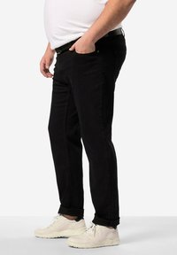 Svarta denimjeans med rak passform, med en klassisk design med fem fickor och diskreta sömmar. Bärs med vita sneakers.