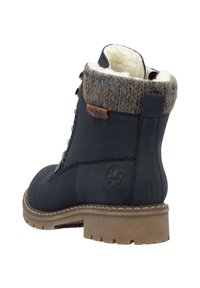 Botte de cheville bleu foncé avec un revers en tricot texturé marron. Dispose d'une semelle robuste et d'un accent en cuir avec un logo. Doublée de matériau doux pour plus de chaleur.