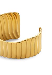 Ancho brazalete de oro con patrones de olas verticales en relieve y un acabado brillante y pulido sobre un fondo blanco.