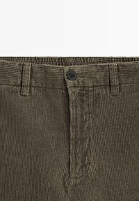 Olivenfarvede corduroy bukser med flad front, med en sort knaplukning og lodret ribbet tekstur langs taljen og kroppen.