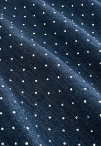 Tela de mezclilla oscura con una textura suave, que presenta pequeños puntos plateados brillantes distribuidos uniformemente por toda la superficie.