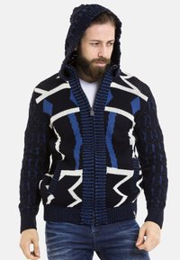 Kapuzensweatshirt mit Reißverschluss in Marineblau, Weiß und Blau. Mit geometrischen Mustern und strukturierten Strickärmeln. Hergestellt aus dickem Garnmaterial.