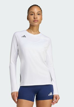 Langermige witte sporttop met grijze logo-accenten en een soepele, lichte stof, gecombineerd met marineblauwe shorts met witte logodetails.