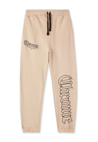 Beżowe spodnie dresowe z elastycznym paskiem, czarnym sznurkiem i dużym czarnym napisem po boku. Miękka, gładka faktura tkaniny.
