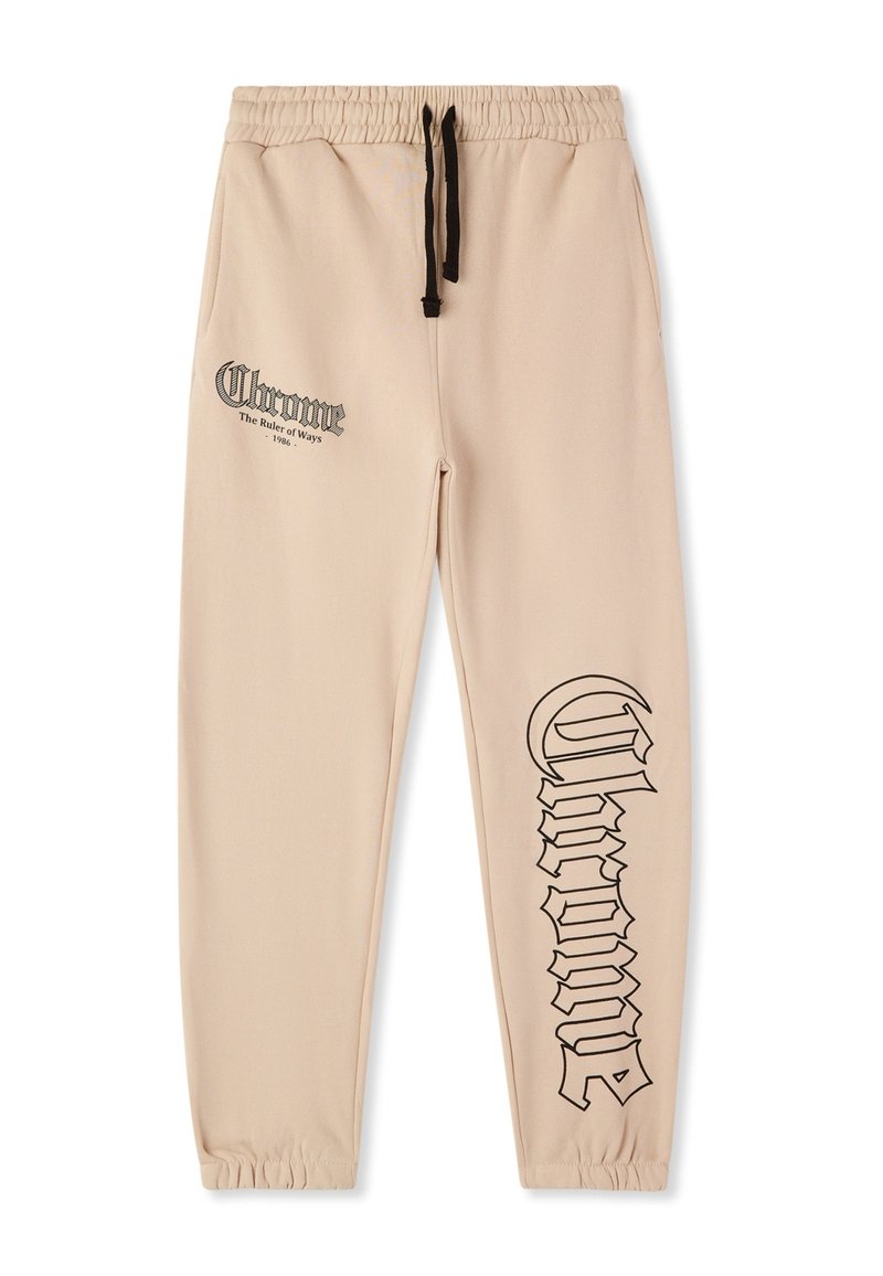Beżowe spodnie dresowe z elastycznym paskiem, czarnym sznurkiem i dużym czarnym napisem po boku. Miękka, gładka faktura tkaniny.
