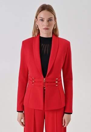 Roter Blazer mit taillierter Passform, scharfen Revers und goldenen Hardware-Details. Aus einem glatten Stoff gefertigt, mit einer taillierten Taille und dekorativen Verschlüssen.