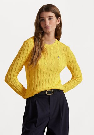 Pullover giallo a maglia con collo rotondo e maniche lunghe, caratterizzato da un logo discreto sul petto. Abbinato a pantaloni scuri a vita alta.