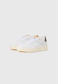 Sneaker bianche in pelle con accenti testurizzati, suola in gomma beige chiaro e dettaglio del logo; presenta una combinazione di materiali lisci e scamosciati.
