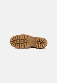 Semelle de botte en caoutchouc marron avec un motif de bande de roulement profond et des rainures rectangulaires. Présente une surface texturée pour une bonne adhérence et stabilité.
