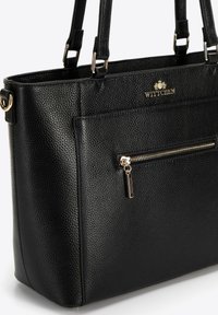 Borsa tote in pelle nera con texture e hardware dorato. Presenta una tasca con zip anteriore e due manici. Nome del marchio in rilievo sulla parte frontale.