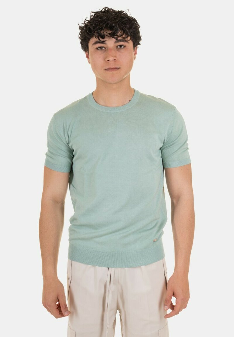 Maglione corto a maniche corte di colore verde chiaro, con scollatura a girocollo rigata, forma aderente e piccolo logo nella parte inferiore sinistra.