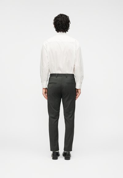 Λευκό πουκάμισο με μακριά μανίκια και λεία υφή, συνδυασμένο με στενά σκούρα γκρι παντελόνια, με καθαρό σχέδιο και δύο πίσω τσέπες.