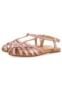 Sandalias metálicas rosas con trenzado en el pie, diseño destalonado y tira en el tobillo. Suela plana con detalles en tonalidad marrón.