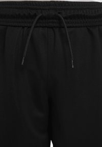 Schwarze Sporthose mit einem elastischen Bund und Kordelzug, glatter Textur und ohne sichtbare Muster oder Verzierungen.