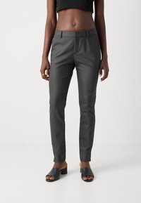 Dunkelgraue, taillierte Hose mit glatter Oberfläche, flachem Frontdesign und Taschen, kombiniert mit schwarzen, offenen Blockabsatzsandalen.