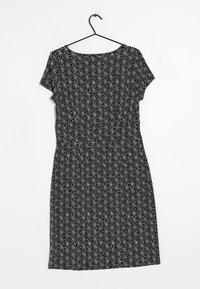 Vestido negro con un patrón de estrellas blancas geométrico, mangas cortas, escote redondo y cintura ceñida, hecho de una tela ligera.
