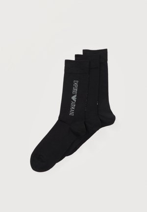 Tre paia di calzini neri alla caviglia impilati, con il logo bianco "EMPORIO ARMANI" sul lato del paio superiore.