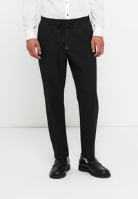 Zwarte, lichte broeken met een elastische tailleband en trekkoord. Ontworpen met een slim fit en een gladde, onbewerkte stof.