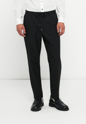 Pantalons noirs légers avec une taille élastique et un cordon de serrage. Conçus avec une coupe fuselée et un tissu lisse, sans texture.