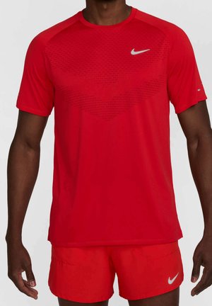 Mann trägt ein rotes Nike T-Shirt mit kurzen Ärmeln und passende rote Shorts, beide mit weißen Nike Swoosh-Logos.