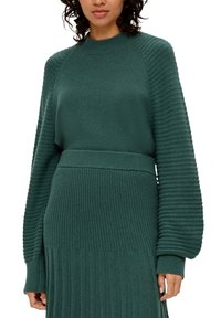 Groene gebreide jurk met ribbelstructuur en getailleerde taille, met ballonmouwen en een ronde halslijn.
