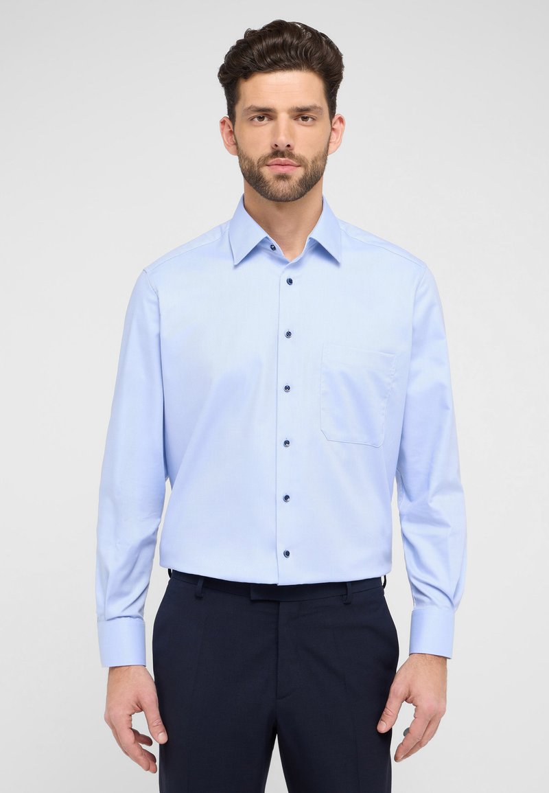 Lichtblauw overhemd met knopen, gemaakt van geweven stof, met een puntkraag, lange mouwen en een borstzak. Donkere knopen contrasteren met de stof.