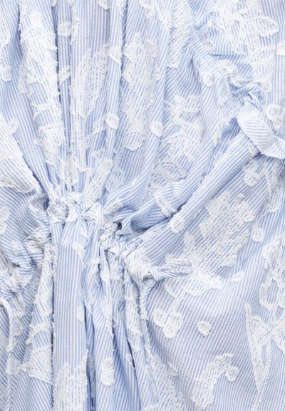 Ραγέ ύφασμα σε μπλε και λευκό με υφασμάτινη λευκή κεντητή λουλουδένια διακόσμηση, μαζεμένο και δεμένο στο κέντρο, που δείχνει πτυχώσεις και ζάρες.